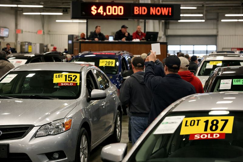 Car auction environment showing vehicles for sale and illustrating additional costs beyond the bid price