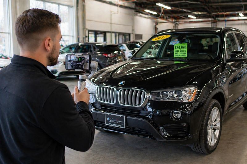 Car dealer taking photos of a vehicle for Facebook ads and online listings
